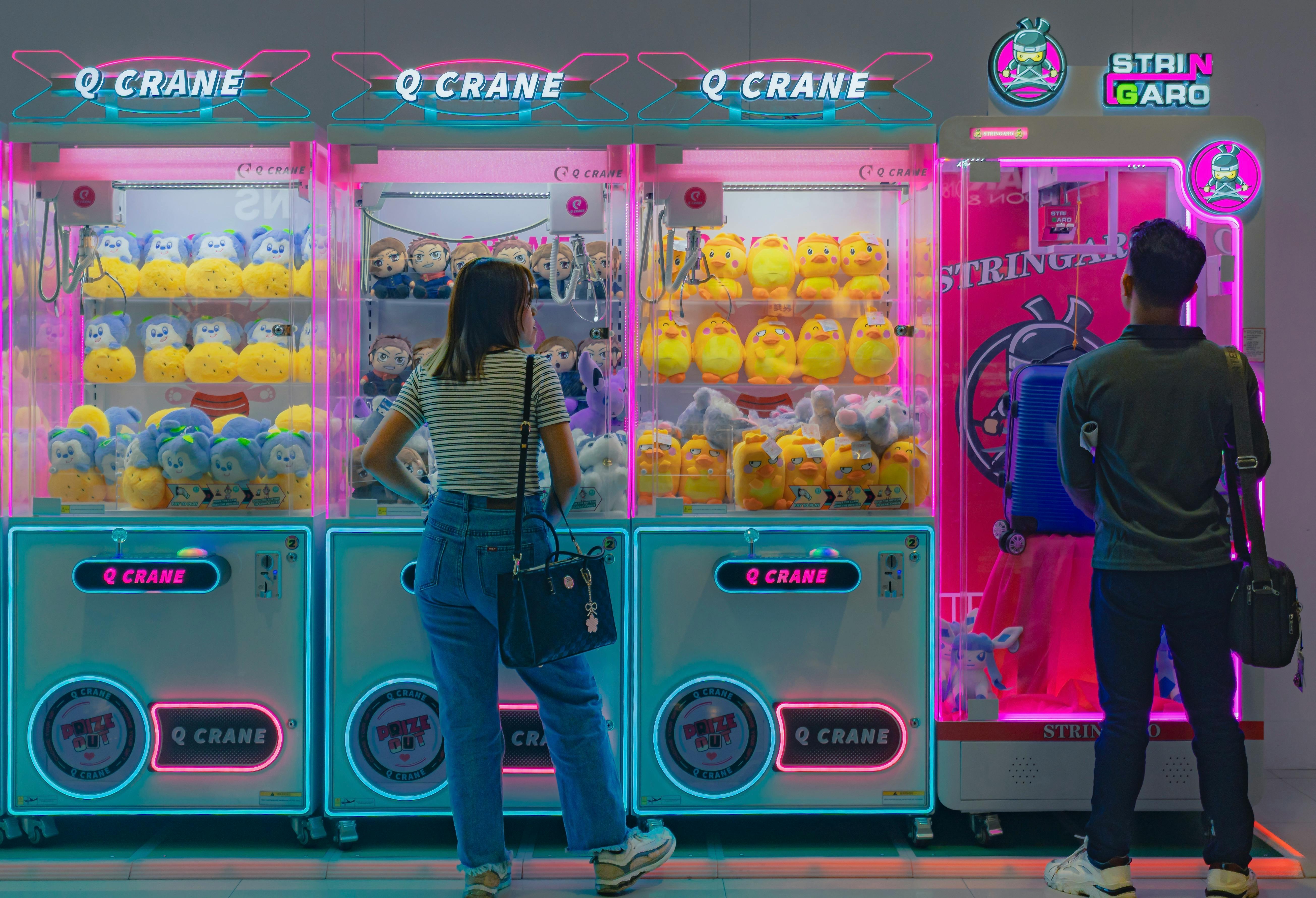 Players at neon-lit claw machines